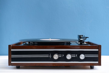 Record player with vinyl disc on table against color background