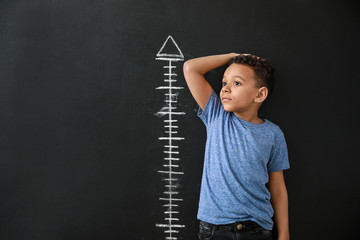African-American boy measuring height near dark wall