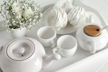Tray with tasty marshmallow and tea on white table
