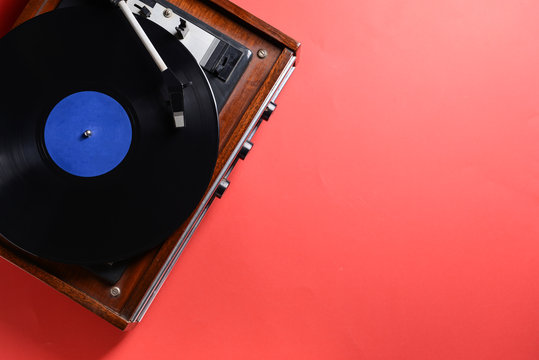 Record player with vinyl disc on color background