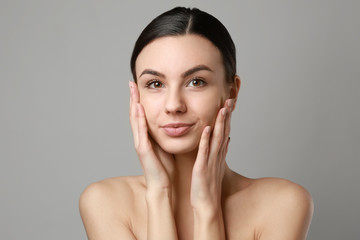 Portrait of beautiful woman with healthy skin on grey background