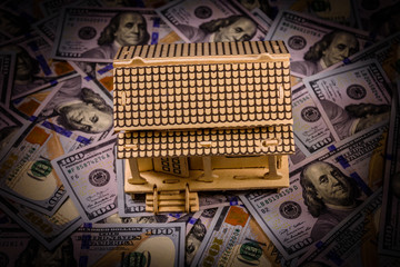 Plywood model of the house and one hundred dollar banknotes. Loan, real estate concept