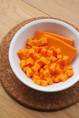 Fresh Butternut squash cut in pieces in a bowl on wooden table