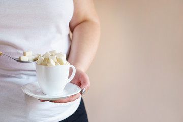 overweight woman holding coffee cup with sugar cubes. sweet and calories content of drinks. unhealthy lifestyle, weight gain, diet, processed products