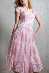Fototapeta premium Girl in pink dress, off the shoulder, with embroidery in the shape of flowers isolated on gray background.
