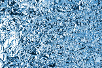 Crumpled blue foil shining texture background, bright shiny cold icy design, metallic glitter...