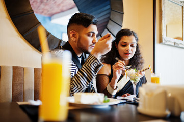 Lovely indian couple in love, wear at saree and elegant suit, posed on restaurant.