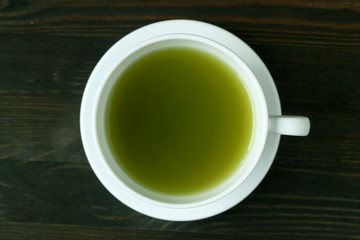 Top View of Vibrant Green Color Hot Matcha Green Tea on Dark Brown Wooden Table