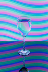 Wine glass with pink, blue, turquoise, orange, green, yellow neon stripes in the background.