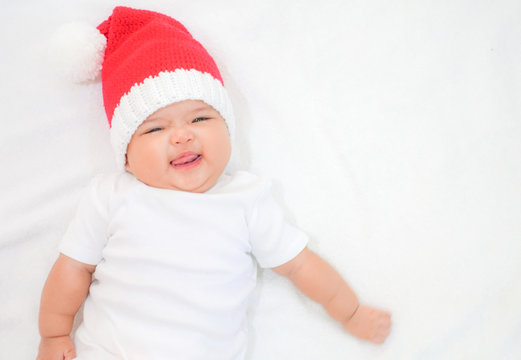 Happy newborn baby wear white shirt and Christmas kneeting hat on white background
