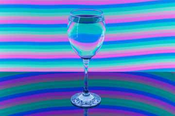 Wine glass with pink, blue, turquoise, orange, green, yellow neon stripes in the background.