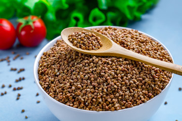 Buckwheat bowl and spoon with fresh ripe vegetables for dietary, healthy food. Fiber and slimming food