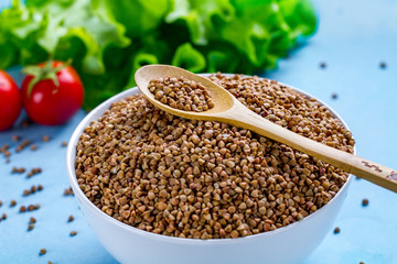 Buckwheat bowl and spoon with fresh ripe vegetables for dietary, healthy food. Fiber and slimming food