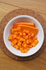 Fresh Butternut squash cut in pieces in a bowl on wooden table