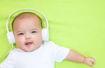 Asian baby girl wears white headphone and white shirt on pink background