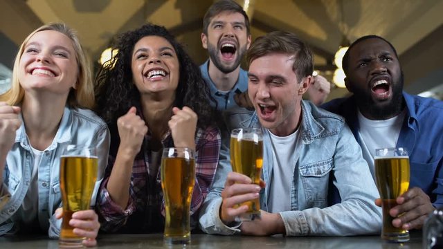 Joyful team supporters screaming and clinking beer glasses, celebrating goal