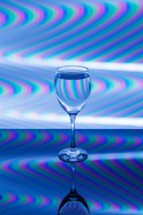 Wine glass with pink, blue, turquoise, orange, green, yellow neon stripes in the background.
