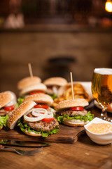Close up of white onion on classic burgers on a wooden tablet