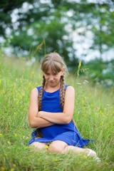 School-age girl in a blue dress with two long braids.