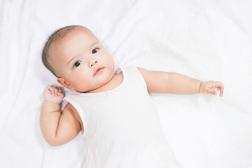 Asian newborn baby girl lying down on white bed