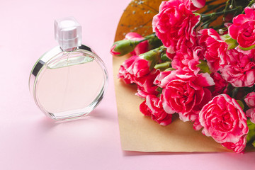 A bottle of woman perfume and a bouquet of flowers on a pink background. Give presents and flowers...
