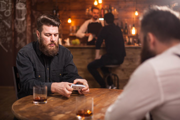 Two bearded hipsters playing a card game in a pub
