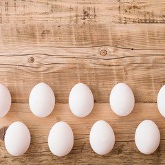 Closeup on white eggs lying on a natural wooden background. Easter festive background.