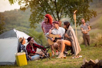 Camping friends in front of tent at music summer festival