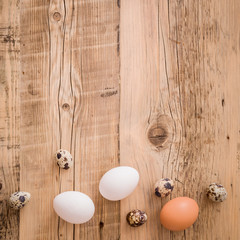 Closeup on fresh chicken and quail eggs lying on a natural wooden table. Easter festive background.