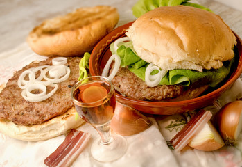Homemade hamburger (burger) and plum brandy on table - delicious meal