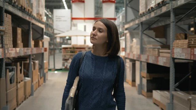 Young female carring packing with goods in shop warehouse.