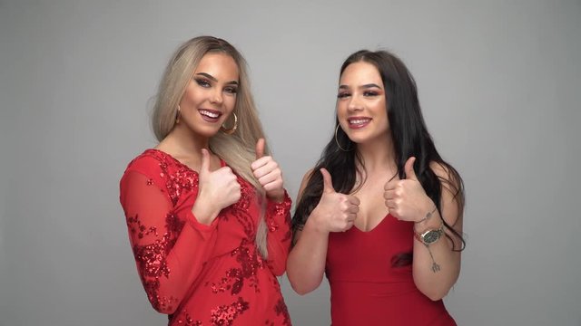 Zwei junge Frauen im roten Kleid Reaktion Daumen hoch