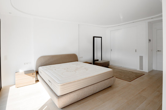 Minimalistic style bedroom in brown and beige tones with new mattress.