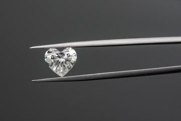Heart shape diamond with tweezers on black background