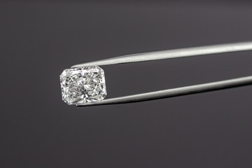 Radiant cut diamond with tweezers on black background