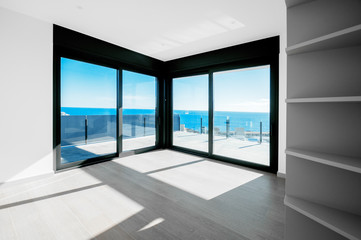 Fototapeta na wymiar Empty rooms in a new house with large windows overlooking the sea. Automatic blinds. Glass partition terrace.