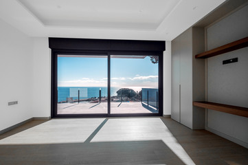 Empty rooms in a new house with large windows overlooking the sea. Automatic blinds. Glass partition terrace.