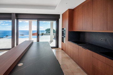 Luxurious wooden kitchen overlooking the sea.  Modern kitchen with an island.