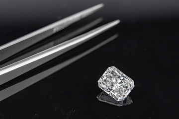 Radiant cut diamond with tweezers on black background