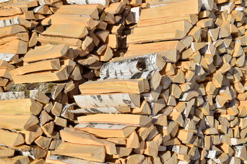 Two rows of stacked split wood. Rustic harvesting for the winter. Spread out the stack of birch firewood. Close up.