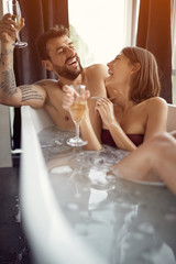 Couple Relaxing In Bubble bath and drinking champagne.