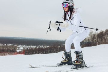 young beautiful girl in stylish sportswear learning to ski, side view full length photo.copy space