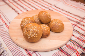 Tasty buns with sesame, on wooden background