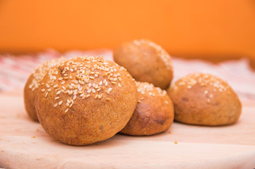 Tasty buns with sesame, on wooden background