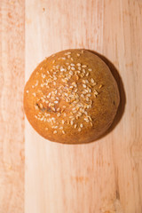 Tasty buns with sesame, on wooden background