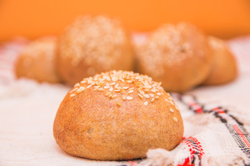 Tasty buns with sesame, on wooden background