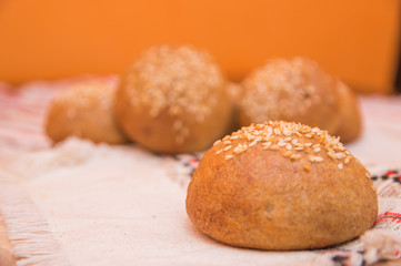 Tasty buns with sesame, on wooden background