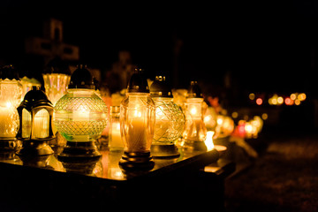 The cemetery, candles burning in lanterns at night during All Saints Day, bokeh of light candle.