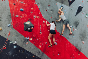 A male and a female spending their leasure time climbing the wall. Man encouraging woman.