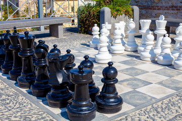 Street chess game. Black and white chess pieces stood in the city park to start the game.